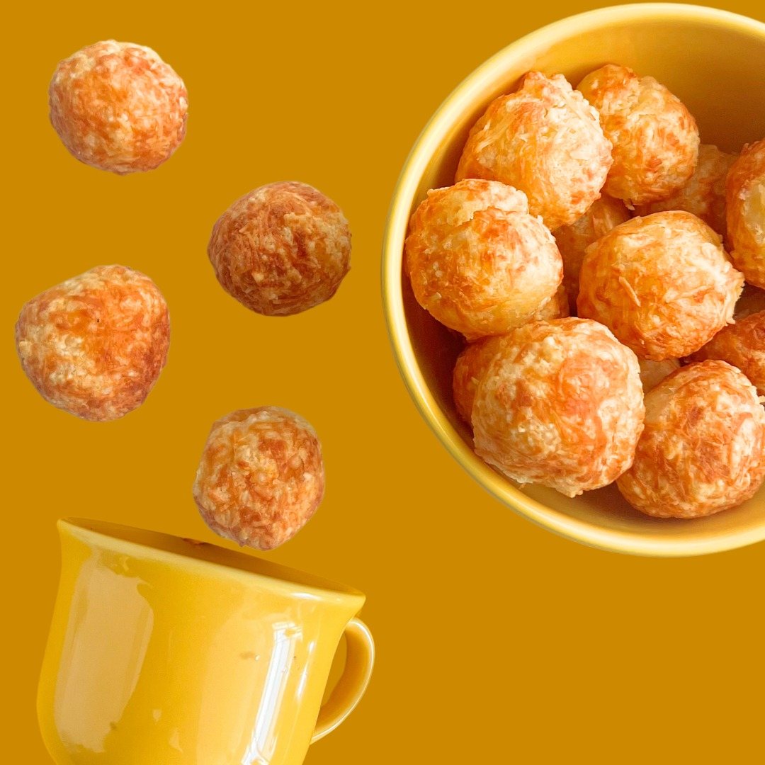 Queijoca cheese puffs falling into a yellow cup