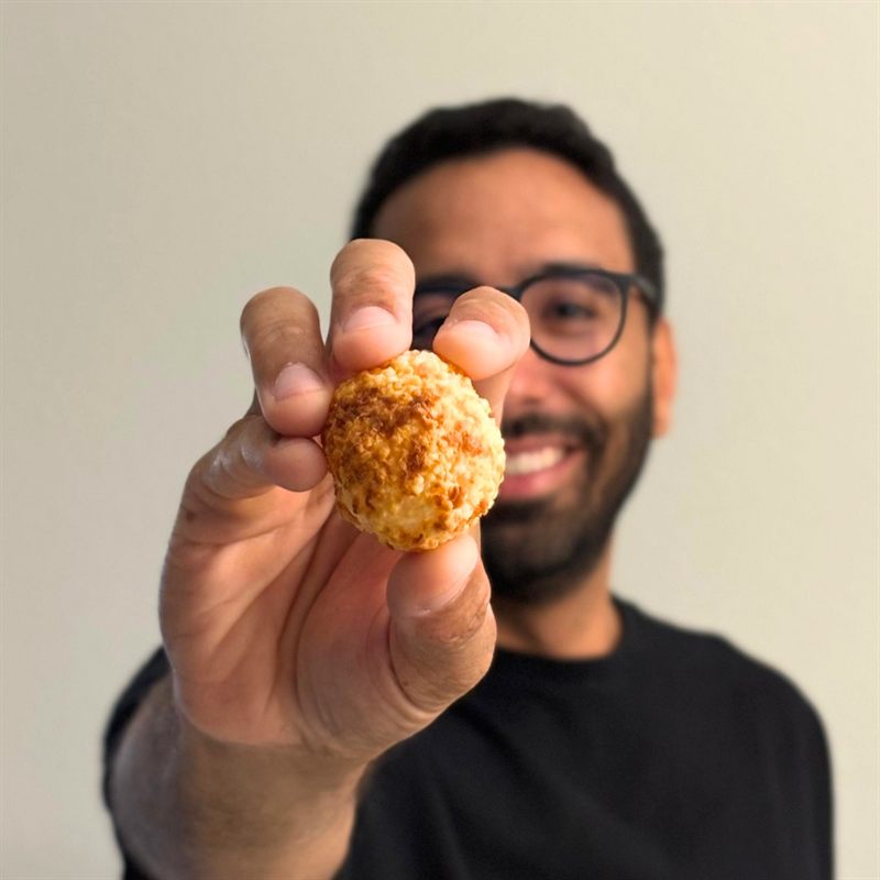 Man smiling and holding a Queijoca cheese puff