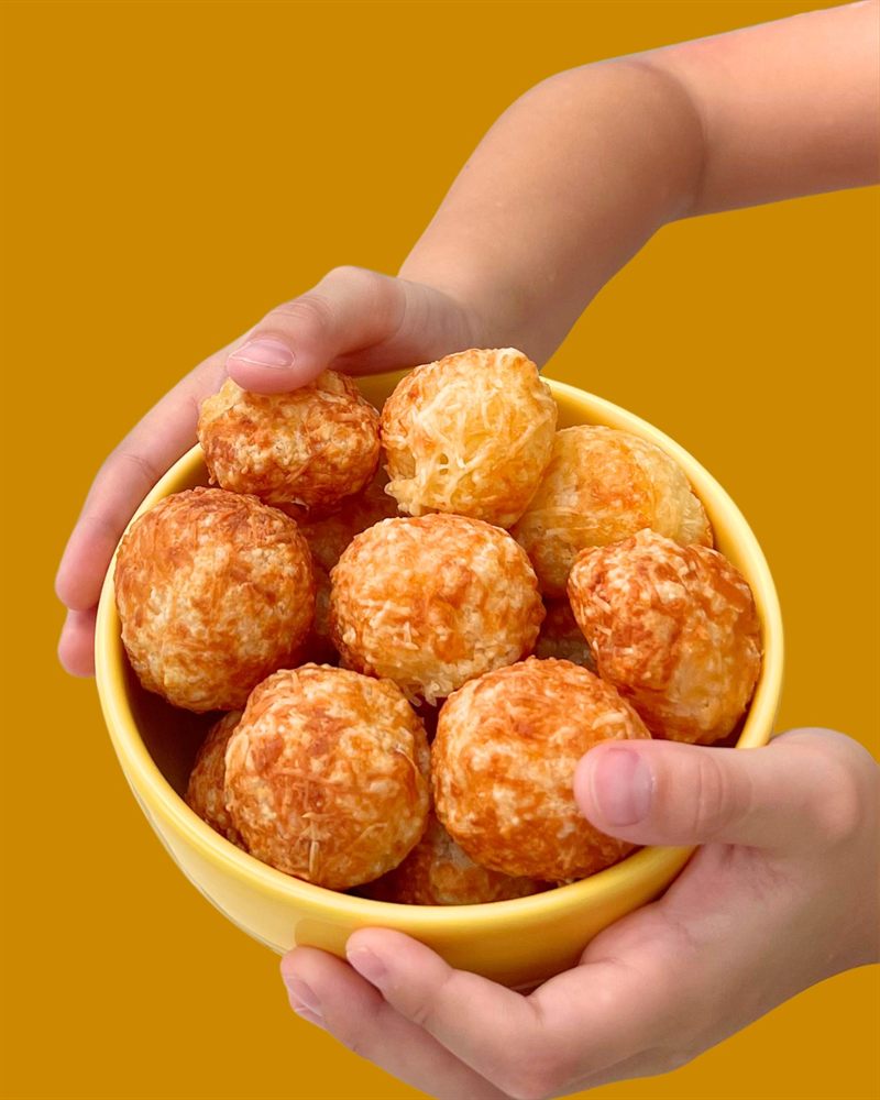 Woman playfully holding two cheese puffs over her eyes