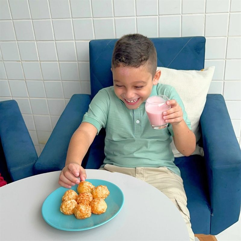 Happy kid with a plate of Queijoca puffs and a smoothie